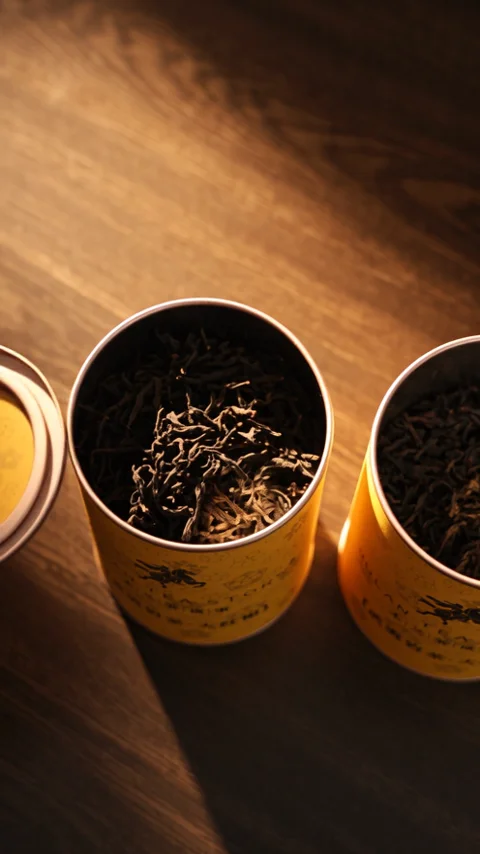 Dry tea in a gold caddy, warm light raking across the mouth